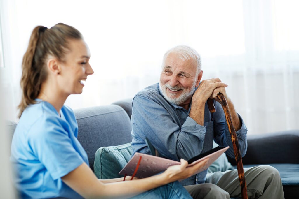 Doctor or nurse caregiver showing a brochure to  senior man at home or nursing home