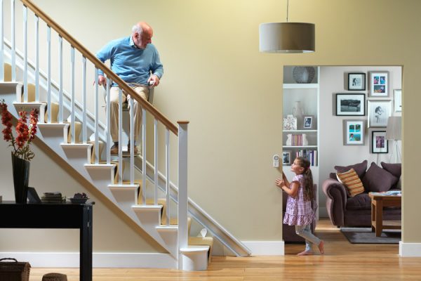 older man rides stairlift while young girl observes